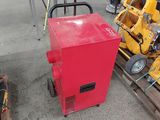 une machine rouge posée sur une palette, à côté d'une pile de palettes