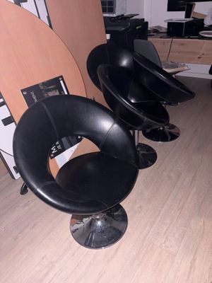 trois fauteuils en cuir noir dans une pièce où une planche de surf est accrochée au mur