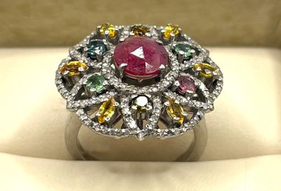 un gros plan d'une bague ornée d'une pierre rose entourée de pierres multicolores