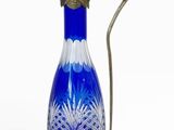 pichet en verre bleu et blanc muni d'une anse en métal, sur fond blanc