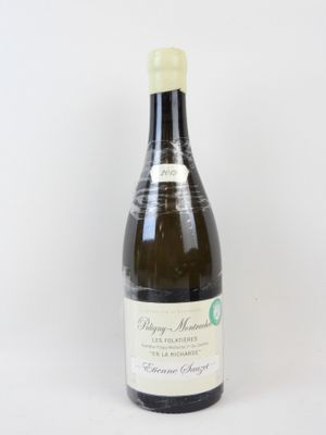 une bouteille de vin posée sur une table à côté d'un mur blanc