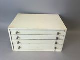 an image of a small white chest of drawers on a table