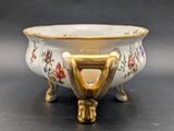 a white bowl with a gold handle sitting on a table