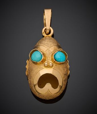 un gros plan sur un pendentif en or représentant un visage aux yeux bleus