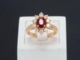 a close up of a gold ring with a ruby and diamond center