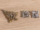 three pieces of silver and gold jewelry on a wooden table