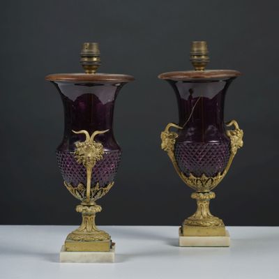 une paire de vases en verre violet rehaussés de touches dorées, posés sur une table blanche