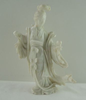 une statue représentant une femme vêtue d'une robe blanche, posée sur une table blanche