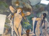un tableau représentant trois nus dans une pièce où est accroché un tableau au mur