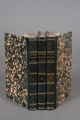 three books are stacked on top of each other on a gray surface