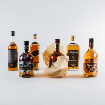 plusieurs bouteilles de différentes sortes d'alcool alignées sur une surface blanche