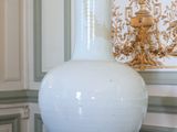 un vase blanc posé sur une table devant un mur