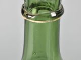 a green glass bottle with a gold rim sitting on a table