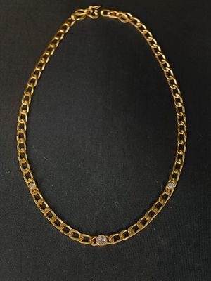 un collier à chaîne en or avec un fermoir en diamant sur fond noir