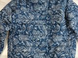 a blue paisley jacket sitting on top of a white table