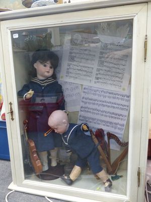 deux poupées dans une vitrine avec des partitions