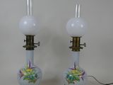une paire de lampes en verre blanc ornées de motifs floraux, posées sur une table