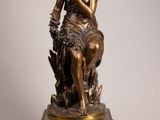 an antique bronze statue of a woman sitting on a tree stump