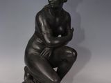a bronze statue of a woman sitting on a rock