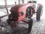 a red tractor that is parked in a barn