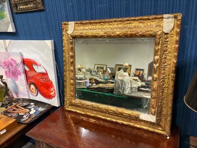 un miroir posé sur une table, à côté d'un tableau et d'une lampe