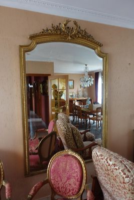 un grand miroir au milieu d'une pièce où se trouvent des chaises et une table