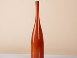an orange vase sitting on top of a white table next to a wall