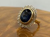 un gros plan d'une bague en or sertie d'une pierre bleue entourée de diamants
