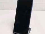 a black cell phone sitting on a stand on a white surface