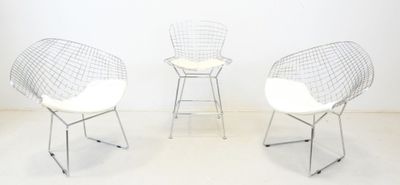trois chaises blanches placées les unes à côté des autres sur un sol blanc