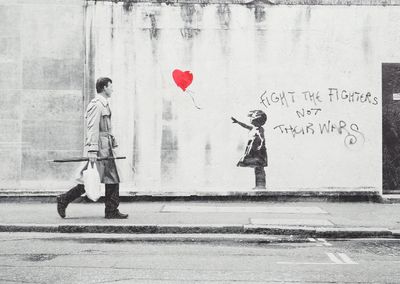 a black and white photo of a man and a girl walking down the street