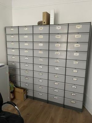 a filing cabinet in the corner of a room next to a chair
