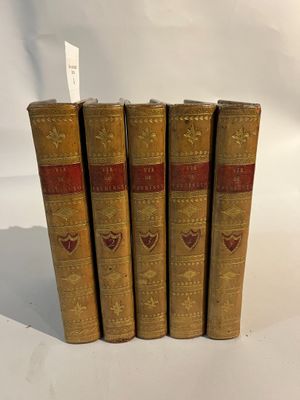 quatre vieux livres posés l'un sur l'autre sur une surface blanche