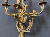 brass plated wall sconce with flowers and leaves on a blue background