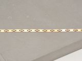 gros plan d'un bracelet en or sur une surface blanche