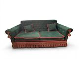 a green couch with red trim and pillows on it