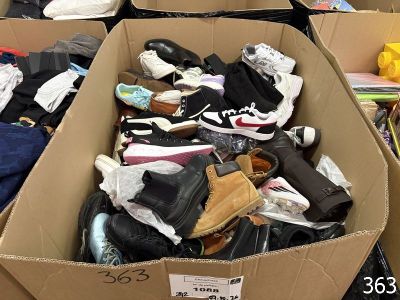 many pairs of shoes in a cardboard box on the floor
