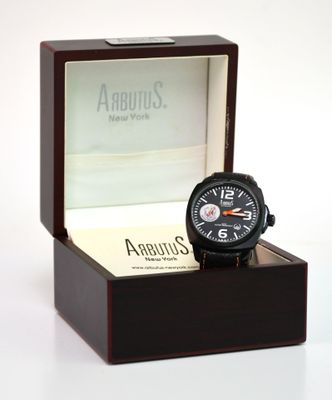 une montre noire dans un coffret en bois posé sur une surface blanche