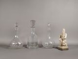 quatre vases en verre et une statue représentant une femme assise, posés sur une table