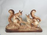 a figurine of a squirrel and a squirrel sitting on a rock