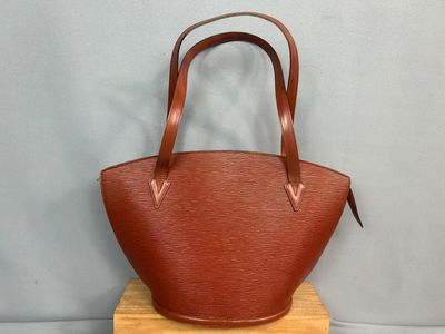 un sac à main en cuir marron posé sur un support en bois