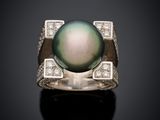 a black pearl and diamond ring on a black surface