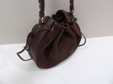 brown sued bucket bag on white surface with white wall in background
