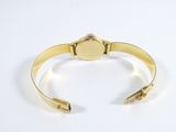 a close up of a gold cuff bracelet with a round clasp