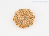 an image of a gold brooch with turquoise stones on a white surface