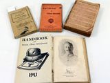 Plusieurs vieux livres sont posés sur une table où se trouvent d'autres vieux livres