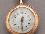 a gold pocket watch with a white dial on it