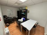 a room with a table, chairs and a refrigerator in it
