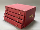 a small red box with three drawers on it