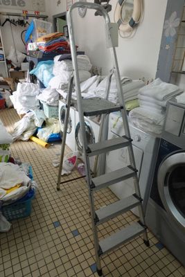 une photo d'une buanderie avec une machine à laver et une échelle